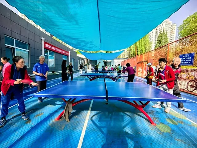 Older adults play table tennis at a community sports area in Beijing, China.