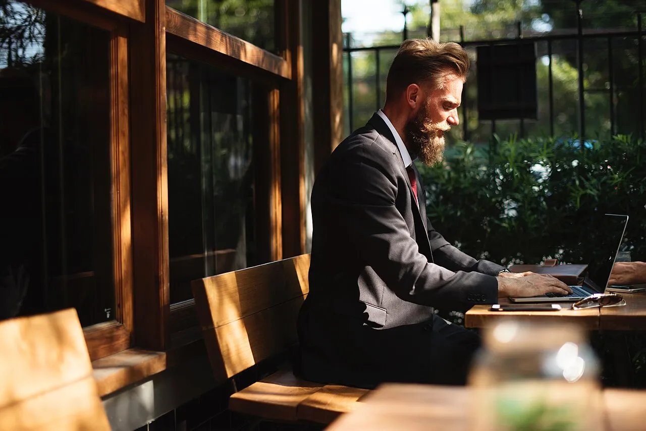A digital nomad works on a laptop in a cafe.