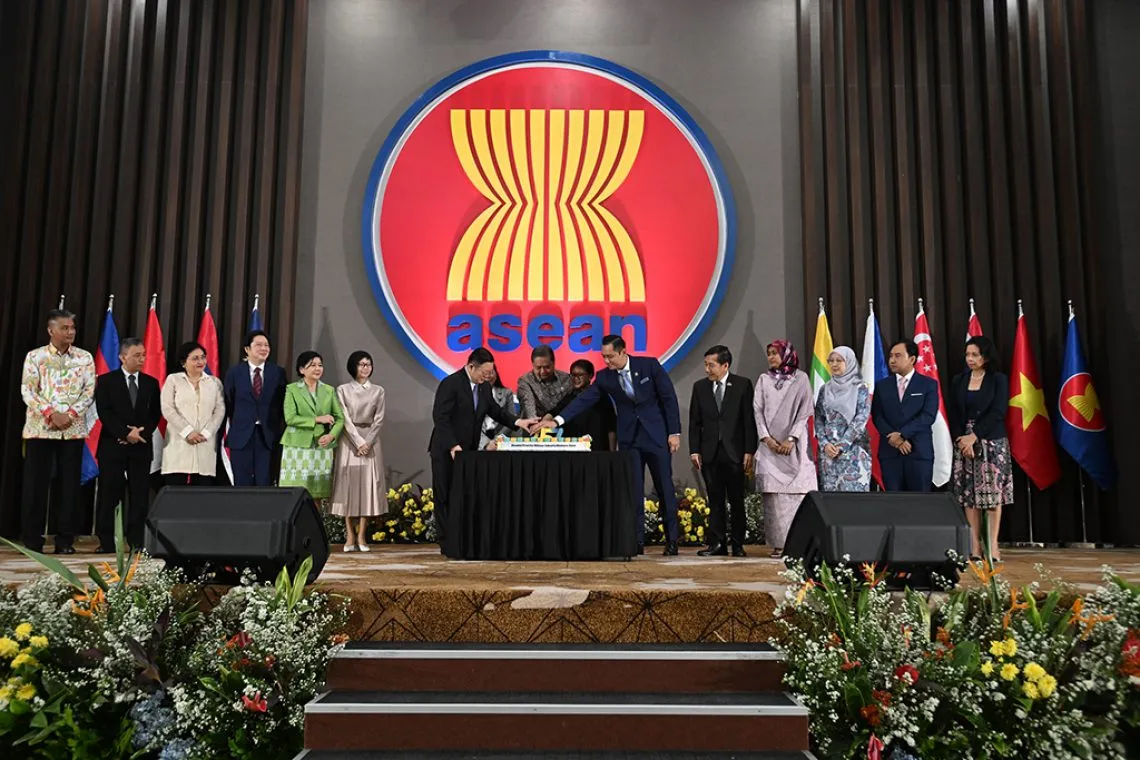 Representatives gather beneath the ASEAN emblem during an ASEAN Day celebration in Jakarta.