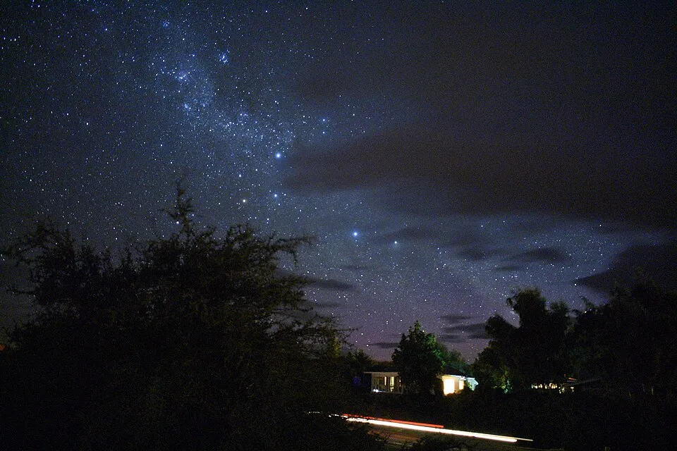 The Milky Way and thousands of stars appear above trees and buildings near Lake Tekapo, New Zealand.