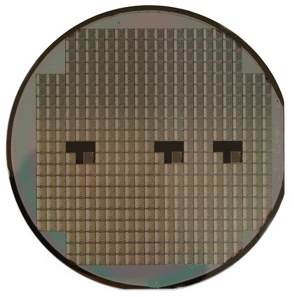 A round silicon wafer contains many small electronic chip designs.