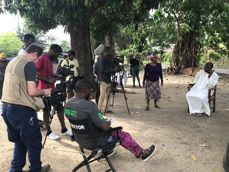 A film crew records a scene outdoors in Nigeria.