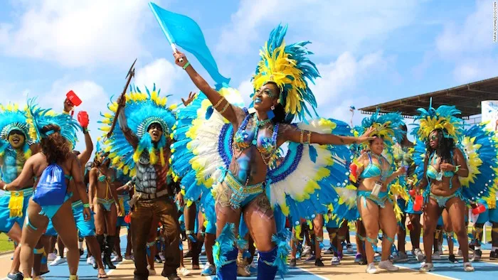 Masqueraders in blue and yellow feathered costumes parade during Barbados’s Crop Over Festival.