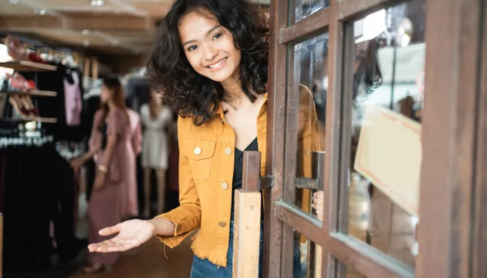 A shop worker welcomes customers at the entrance of a British charity shop.
